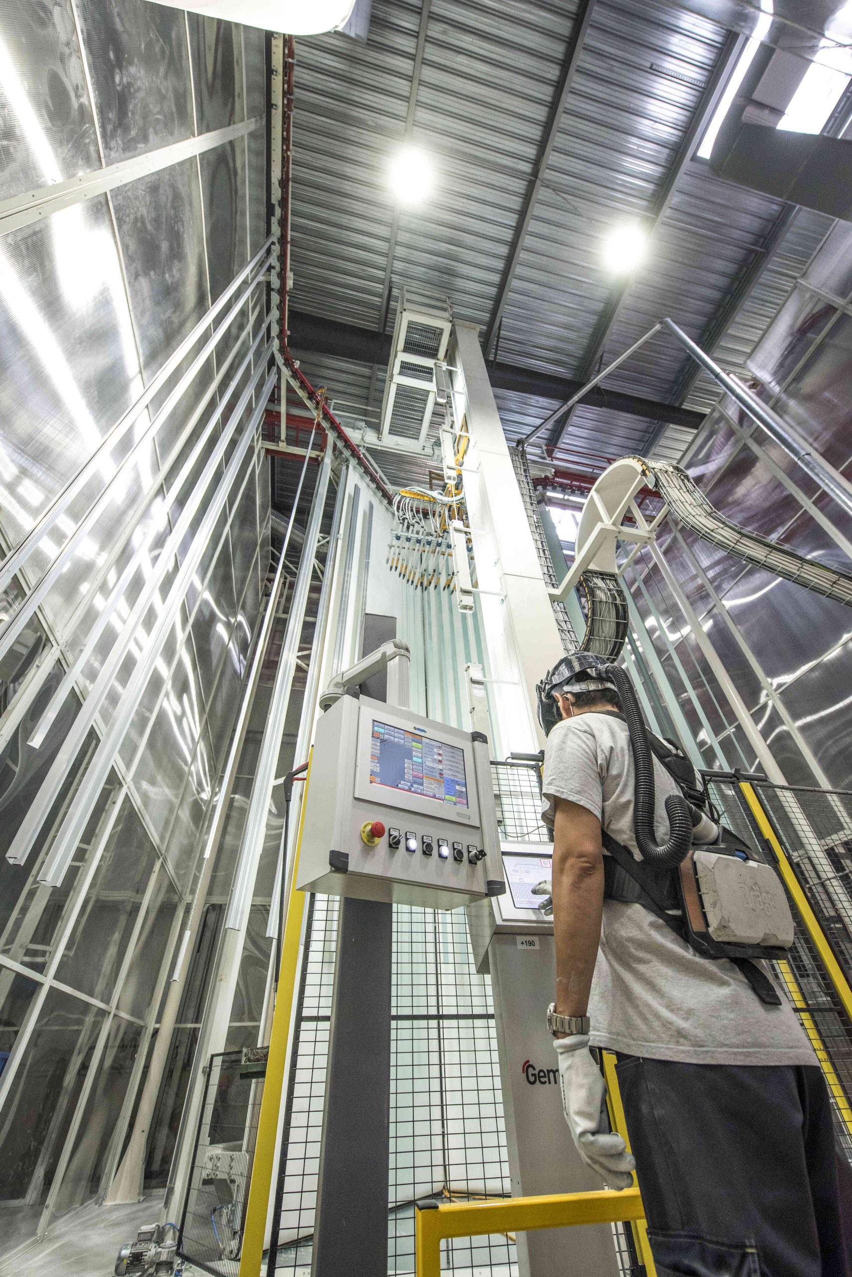 Opérateur supervisant une cabine automatisée de traitement de profilés en aluminium pour la menuiserie