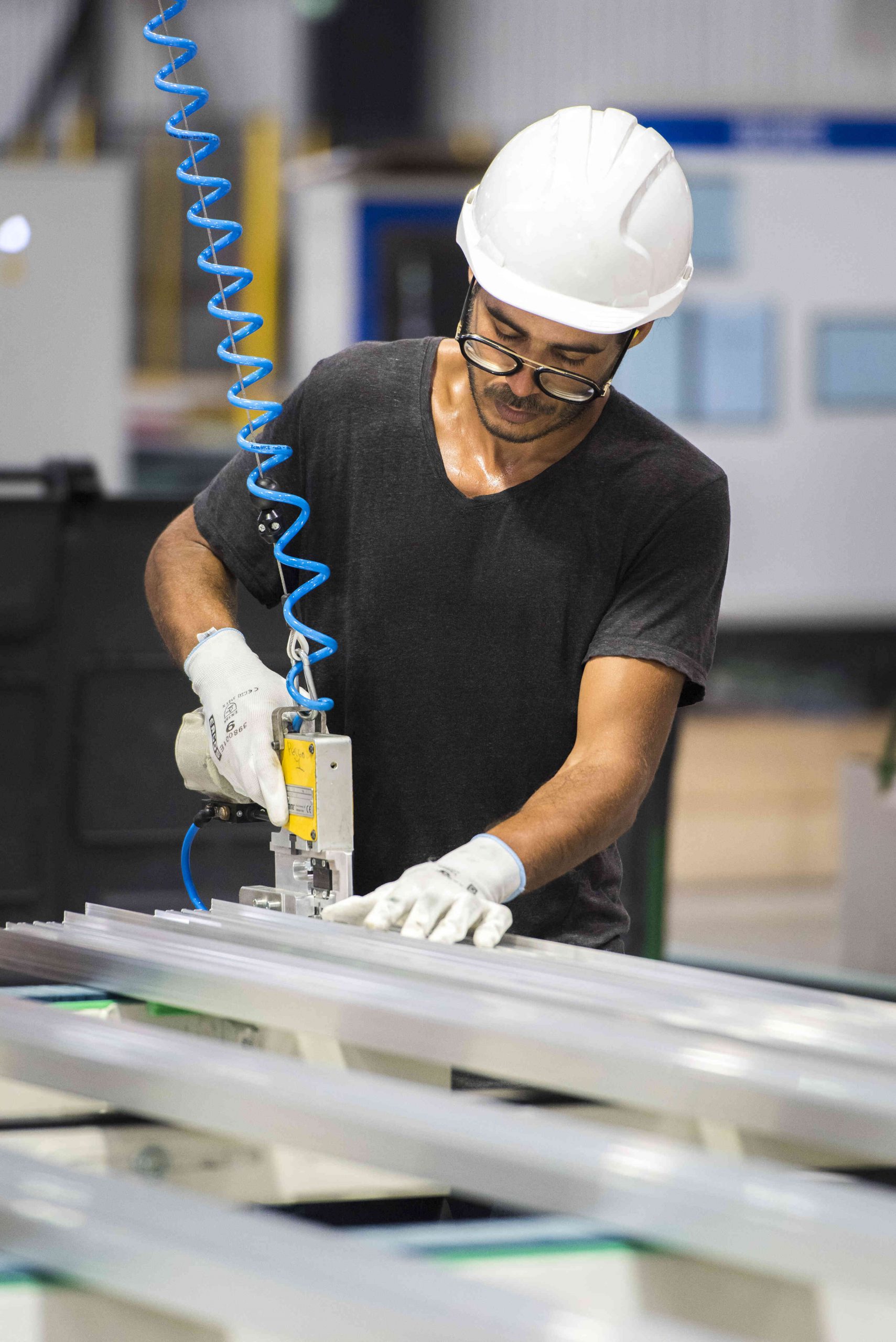 Ouvrier en menuiserie aluminium effectuant un assemblage industriel avec outil pneumatique